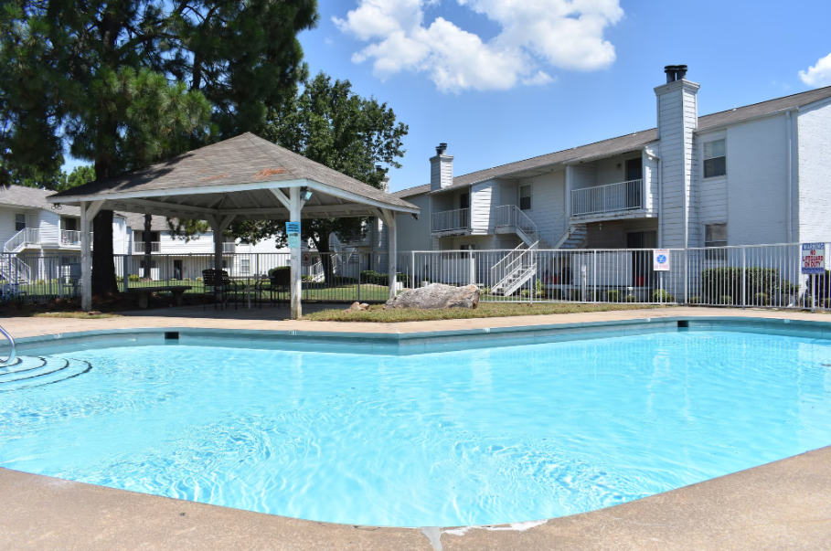 Aerial view of Fort Smith apartment complex with carports, brown roofs, green trees, and a pool