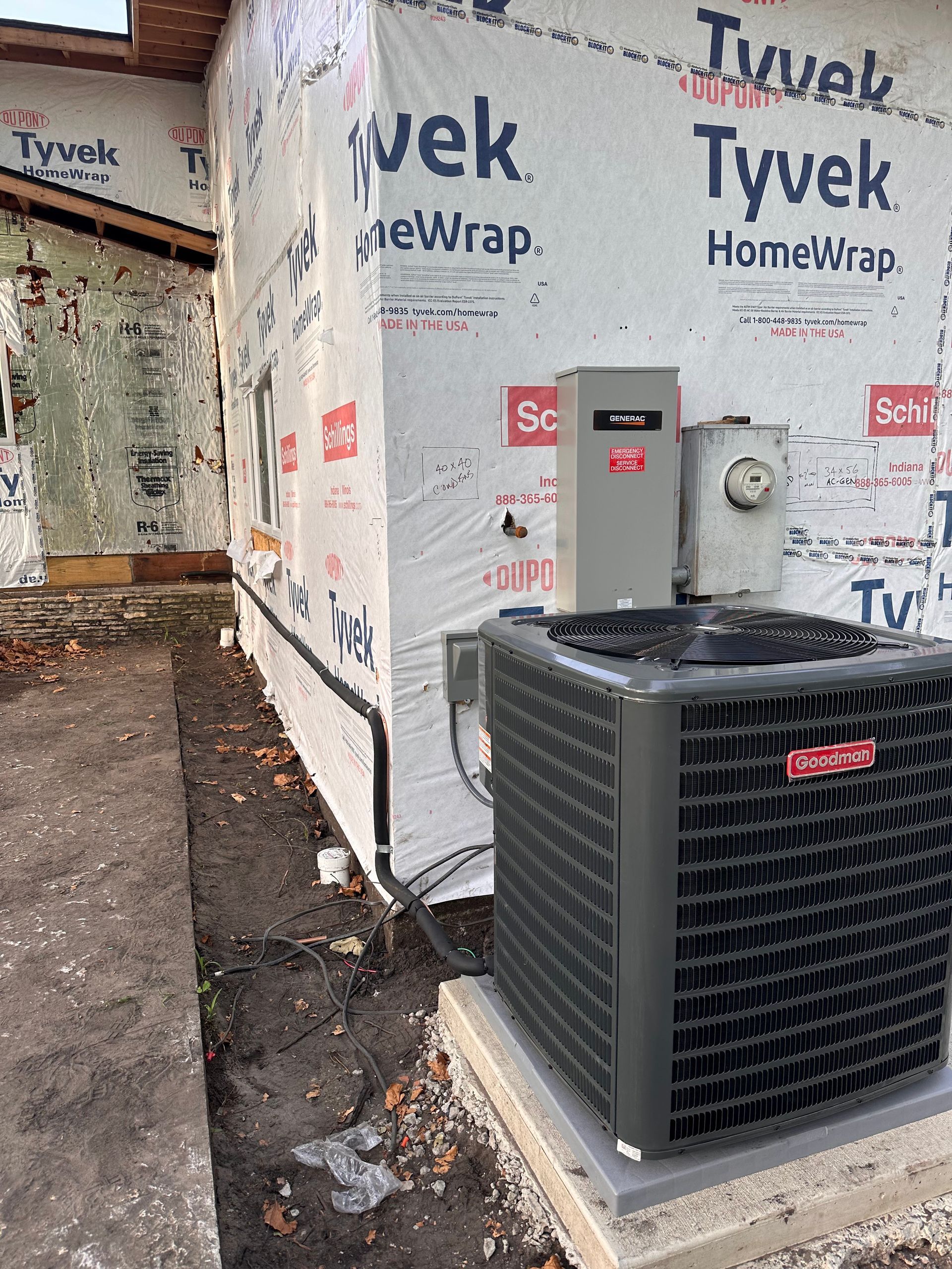House exterior with Tyvek wrap, utility boxes, and a large air conditioner unit beside a narrow walkway