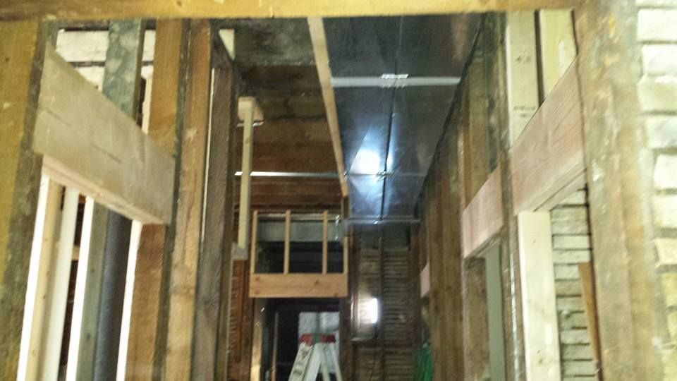 Partially framed interior of a building under construction, with wooden studs and a ladder in a hallway
