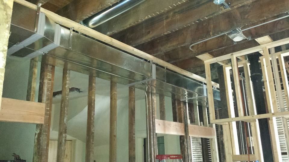 Interior framing of a house under construction, with exposed wooden studs and ceiling beams.