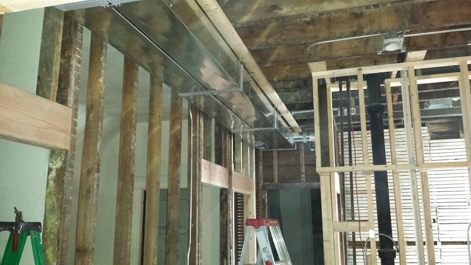 Exposed wooden wall framing and ceiling beams inside a room under construction.