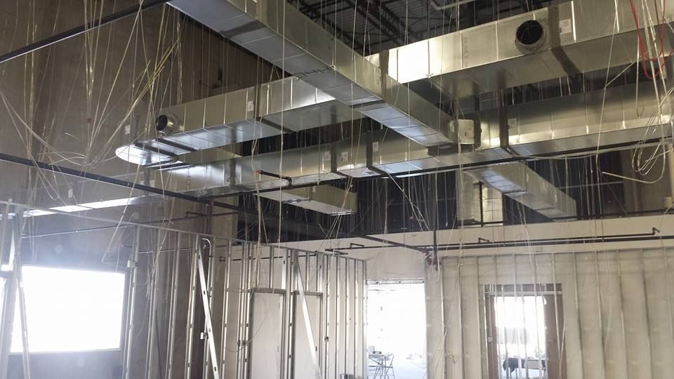 Unfinished ceiling with exposed ductwork and hanging wires in a room under construction