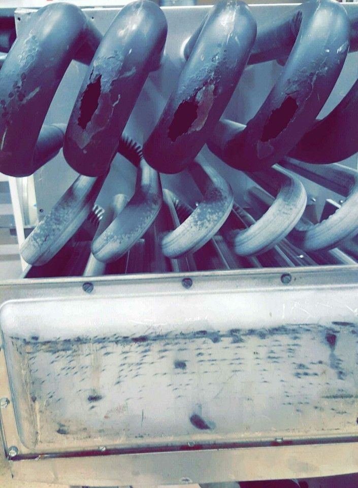 Close-up of a metal coil spring inside a worn industrial machine housing