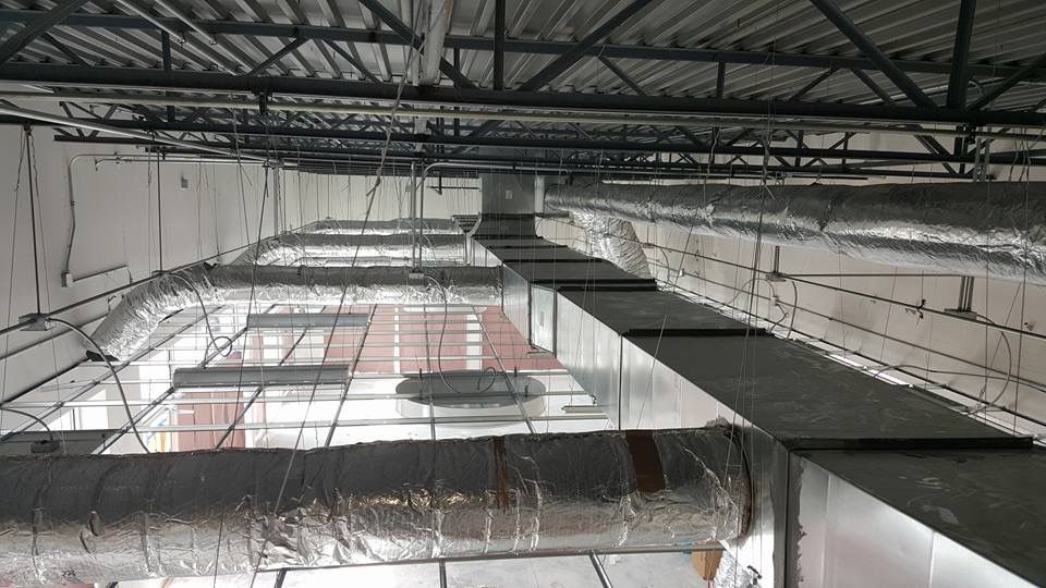 Industrial interior with exposed ceiling beams, ductwork, and metal catwalks in a large unfinished space