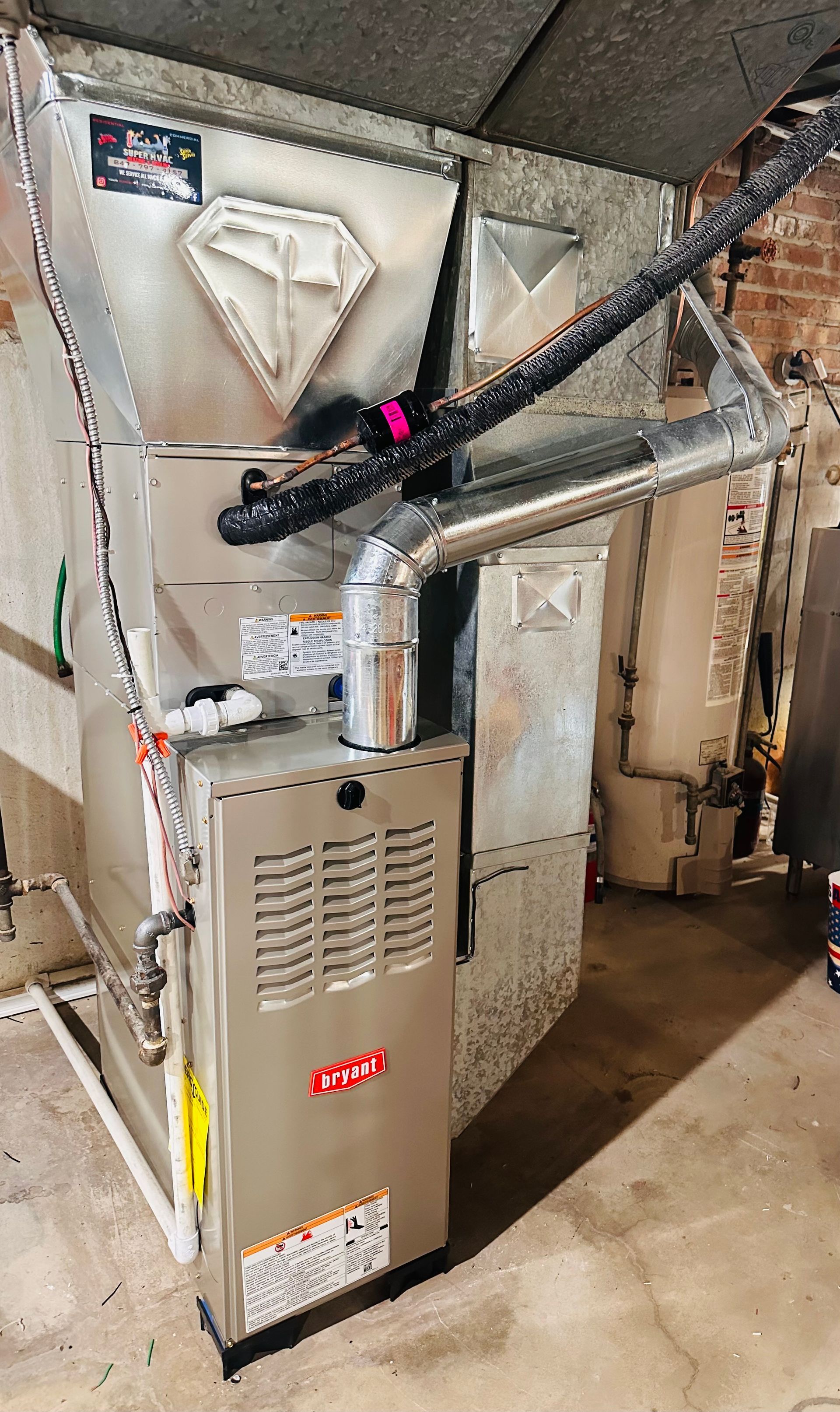 Basement furnace and ductwork with a hanging pipe and metal HVAC unit under low ceiling