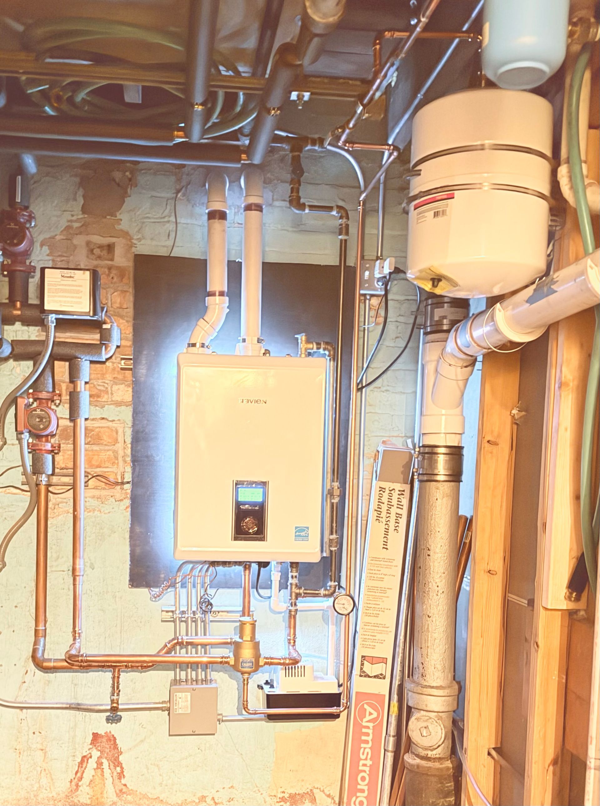 Basement utility room with boiler, water heater, pipes, and electrical panel.
