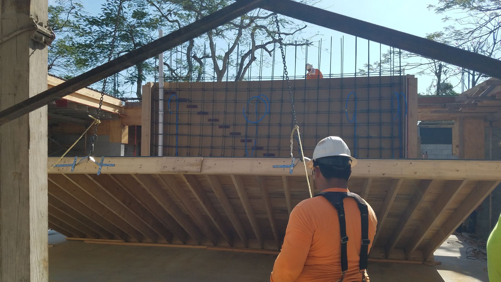 A man wearing a hard hat is standing in front of a building under construction.