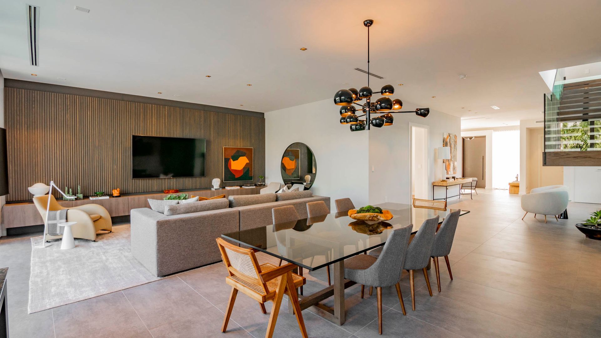 Modern living room with dining area; gray and white color scheme; wooden accent wall.