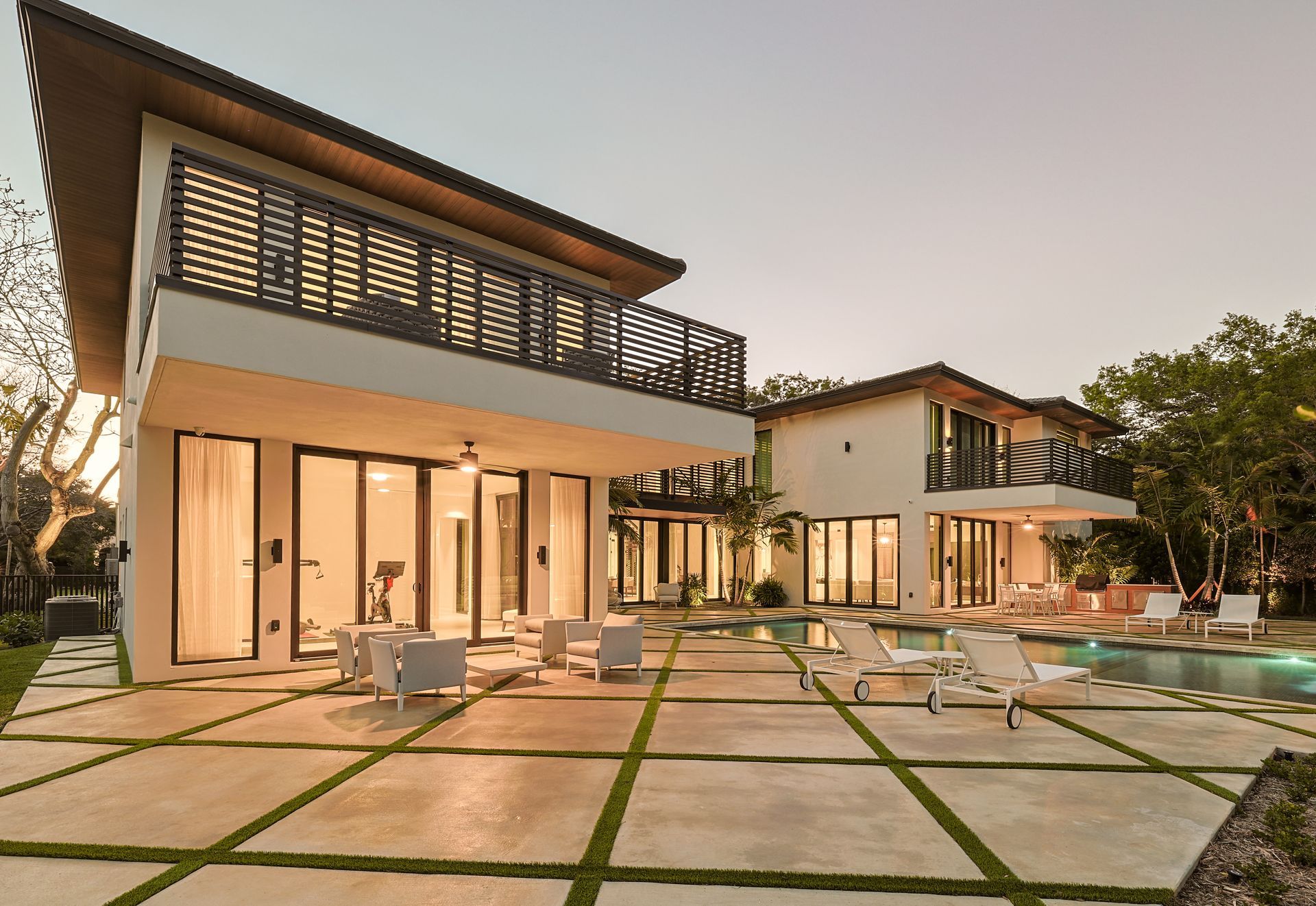 Modern luxury home with pool, patio, and two-story structures; outdoor seating.