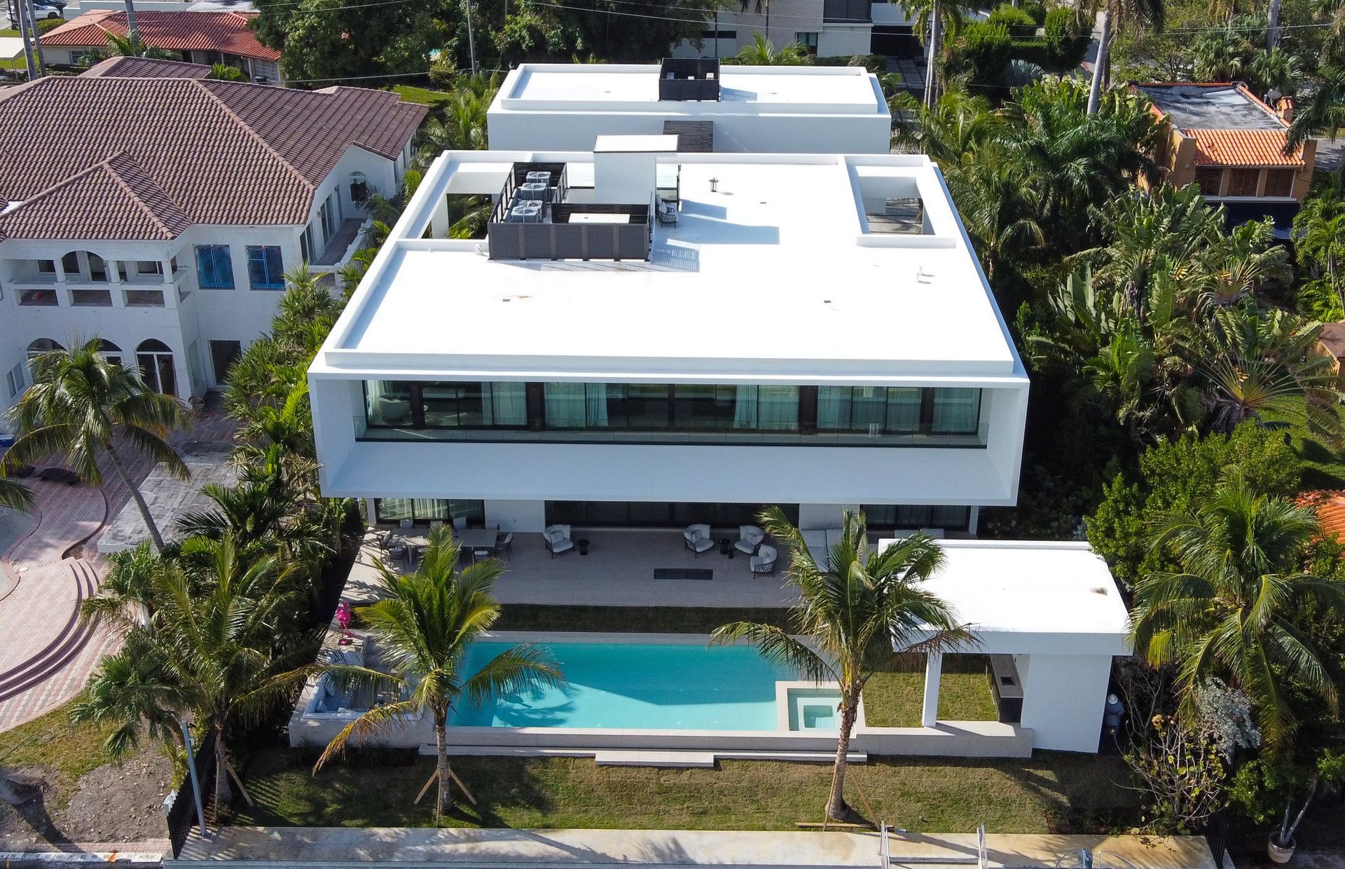 An aerial view of a large white house with a swimming pool