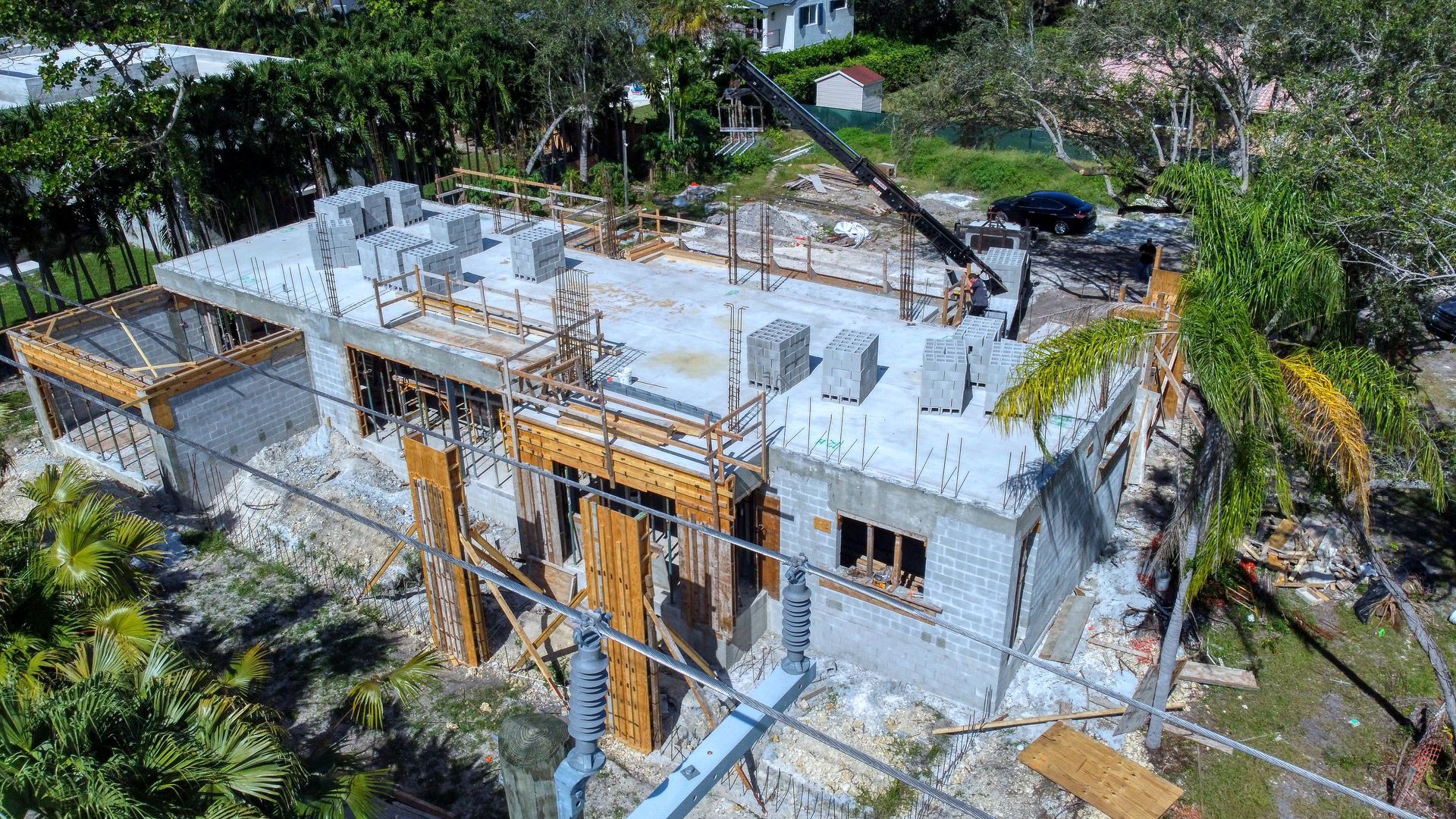 Construction site with a partially built concrete block building. A crane is in the background.
