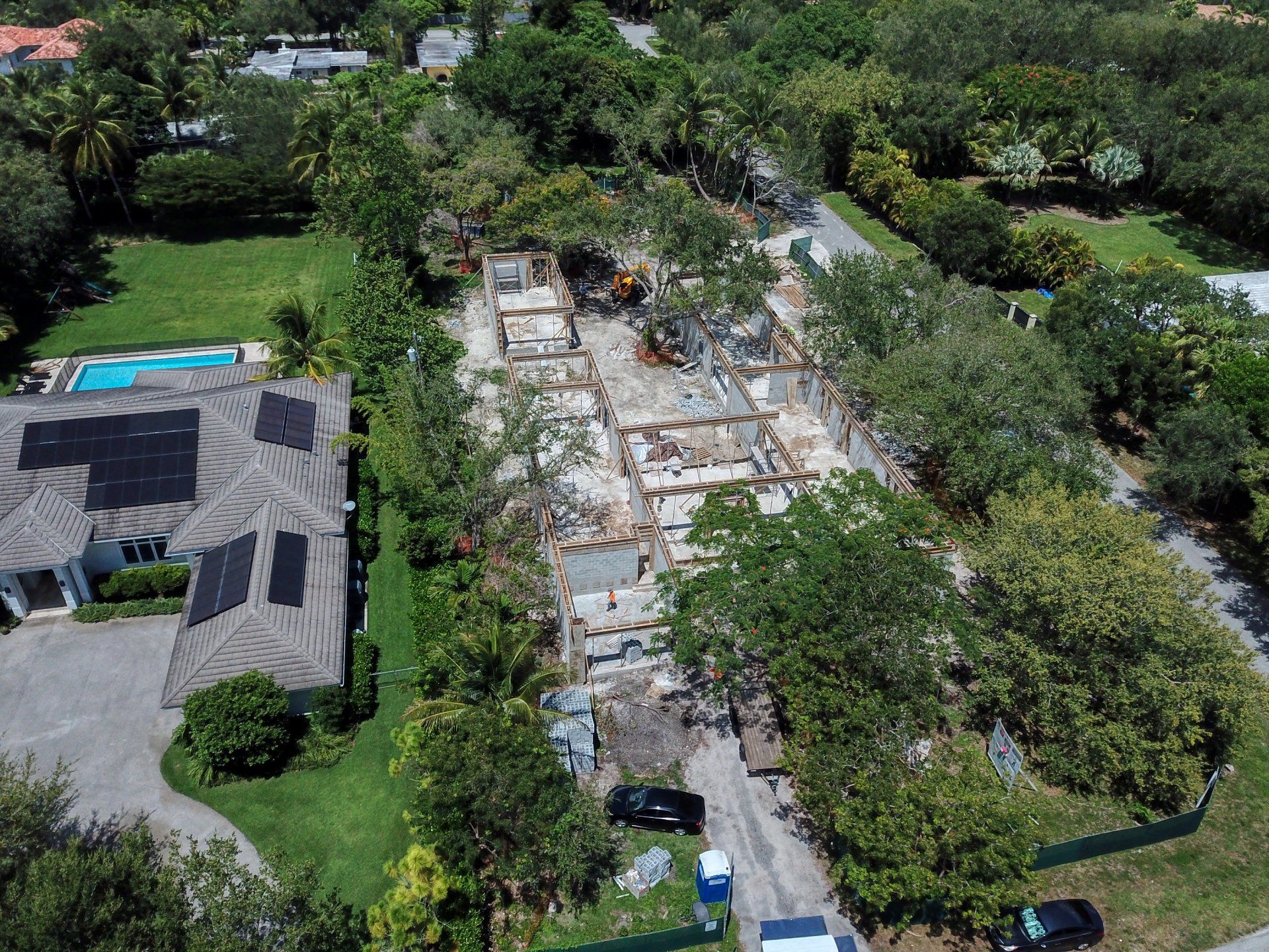 Aerial view of a construction site; building demolition surrounded by trees and residential properties.