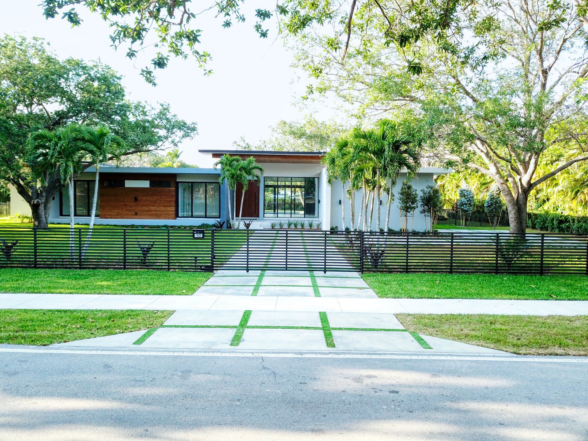 Modern home with wood accents, gray siding, and a black fence along the front yard.