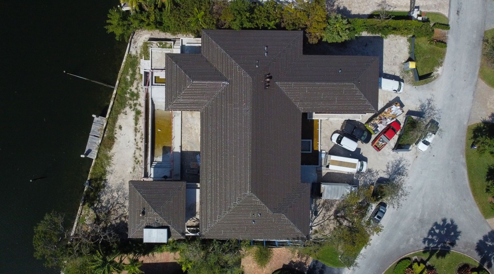 Overhead view of a house with a dark roof and a boat docked on a canal.