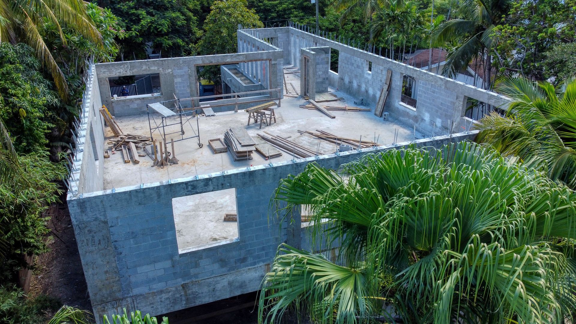 Construction site of a concrete building in a lush green environment, with open walls and exposed beams.