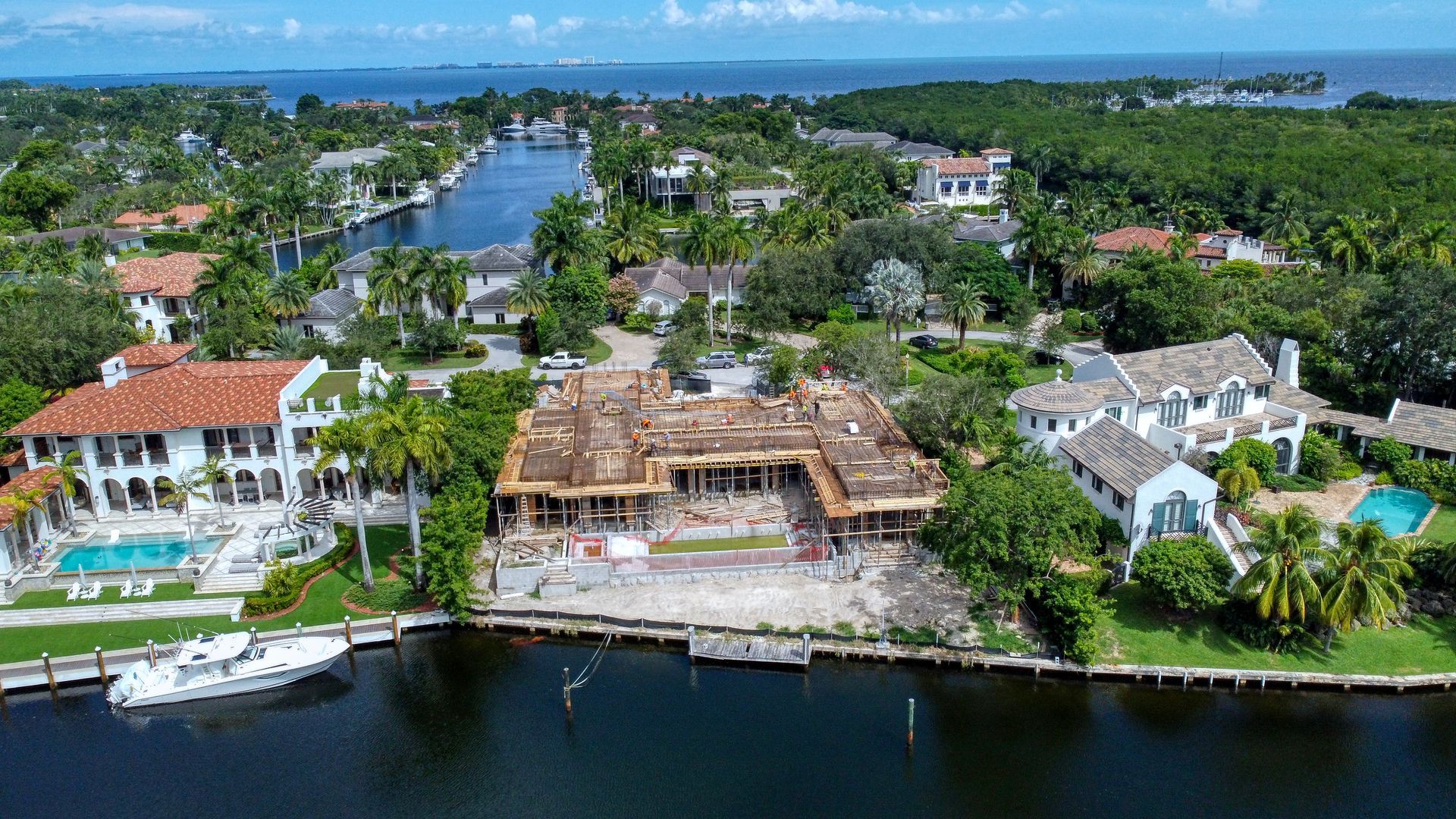 Aerial view of a partially demolished waterfront mansion surrounded by other homes and waterways.