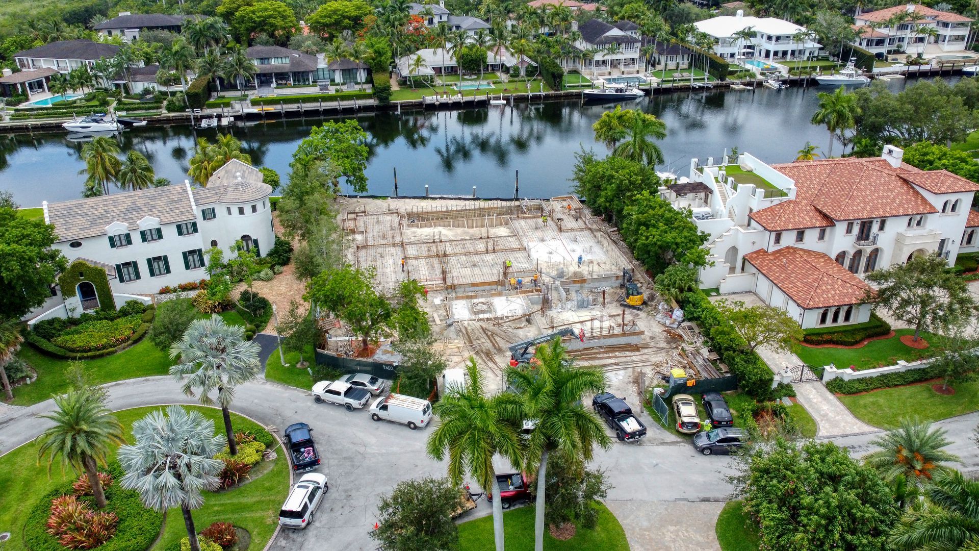 Demolished building site between luxury homes on a waterfront canal.