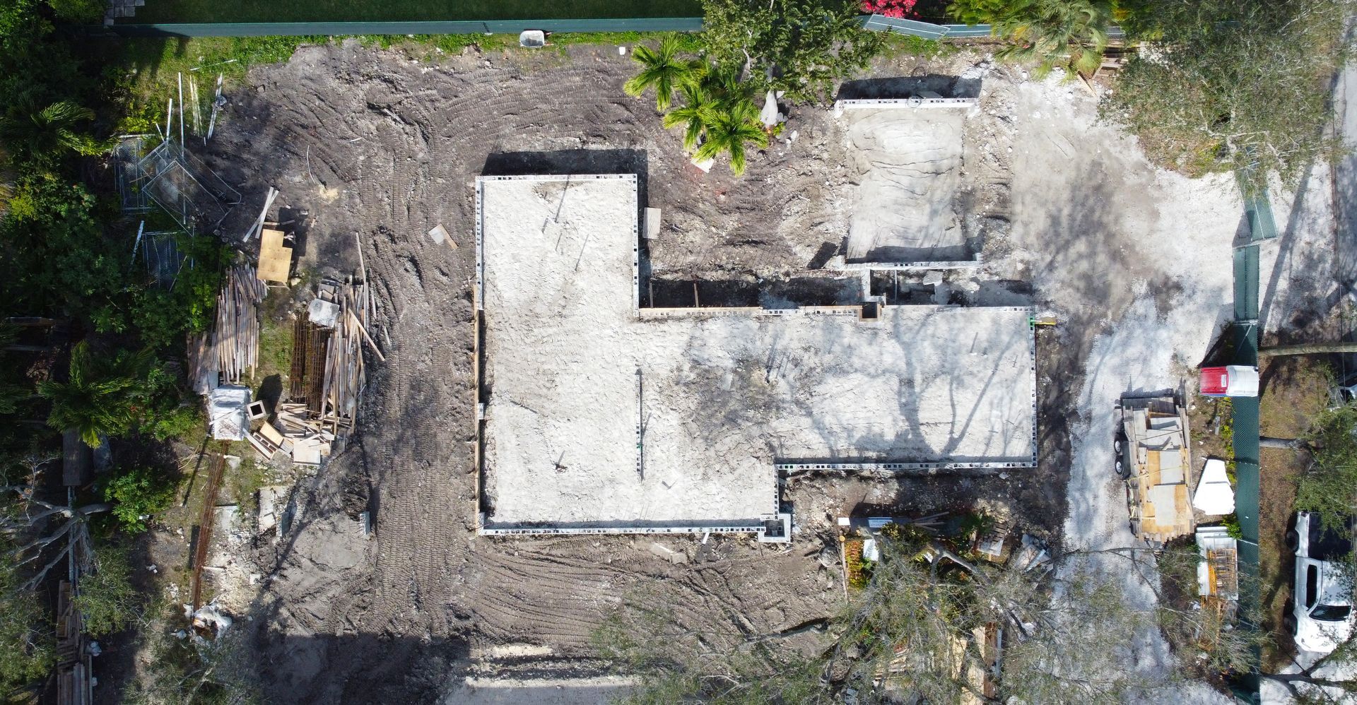 Aerial view of a demolished building foundation surrounded by debris and trees.