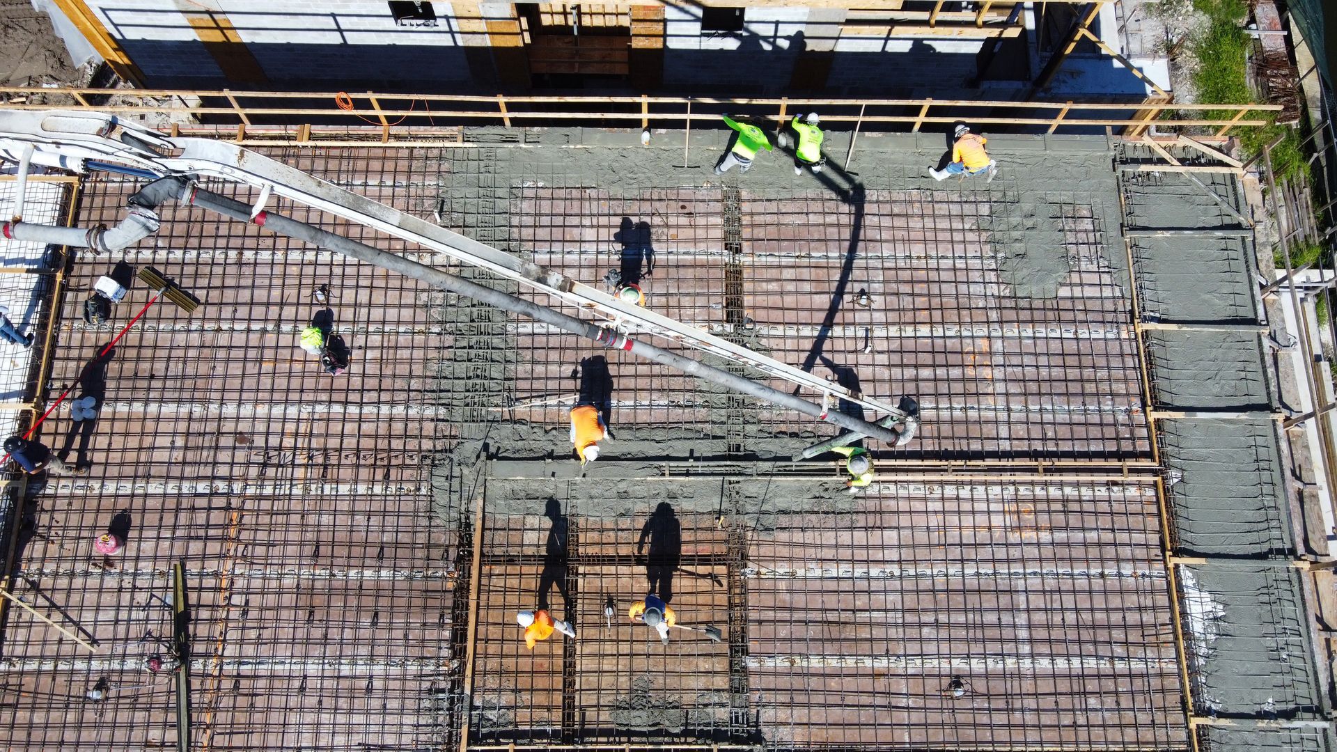 Construction workers pour concrete onto a rebar-covered structure.