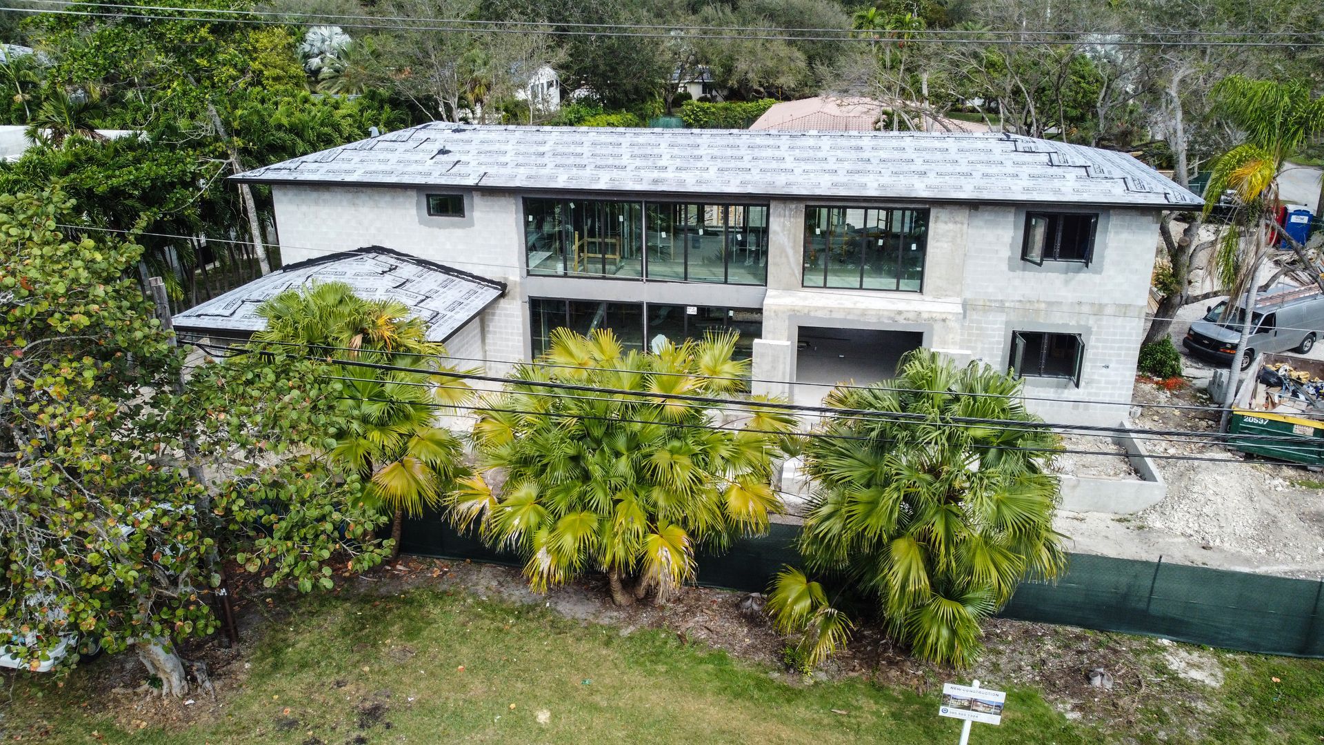 Construction site: Two-story house with unfinished exterior, large windows, and roof tiles.
