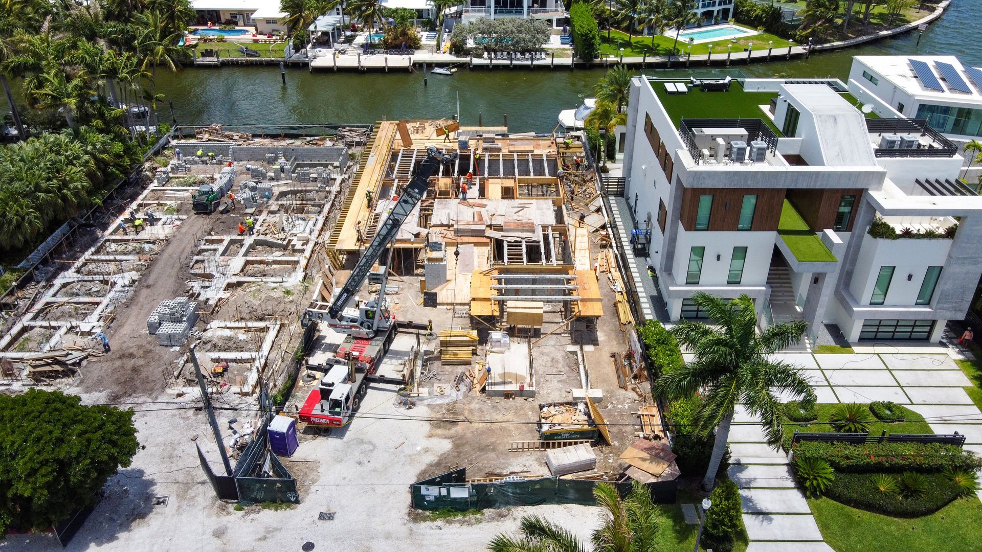 Aerial view of a construction site next to a modern house and waterway.