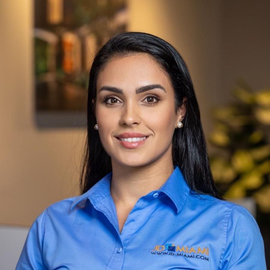 Woman with dark hair smiling, wearing a blue shirt.