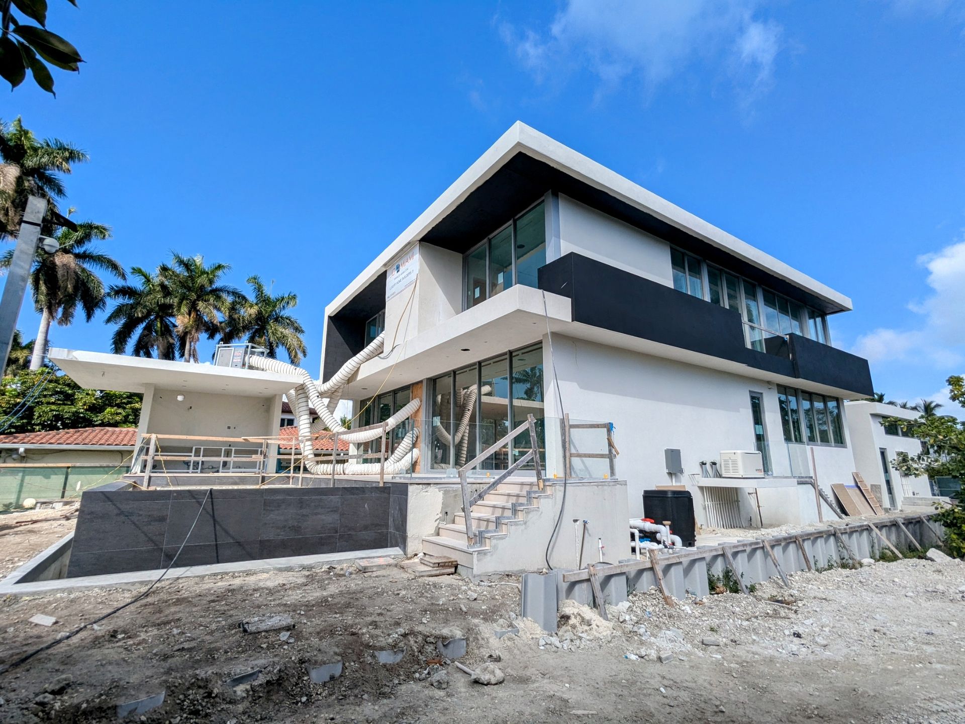 A large white house is being built on top of a dirt hill.