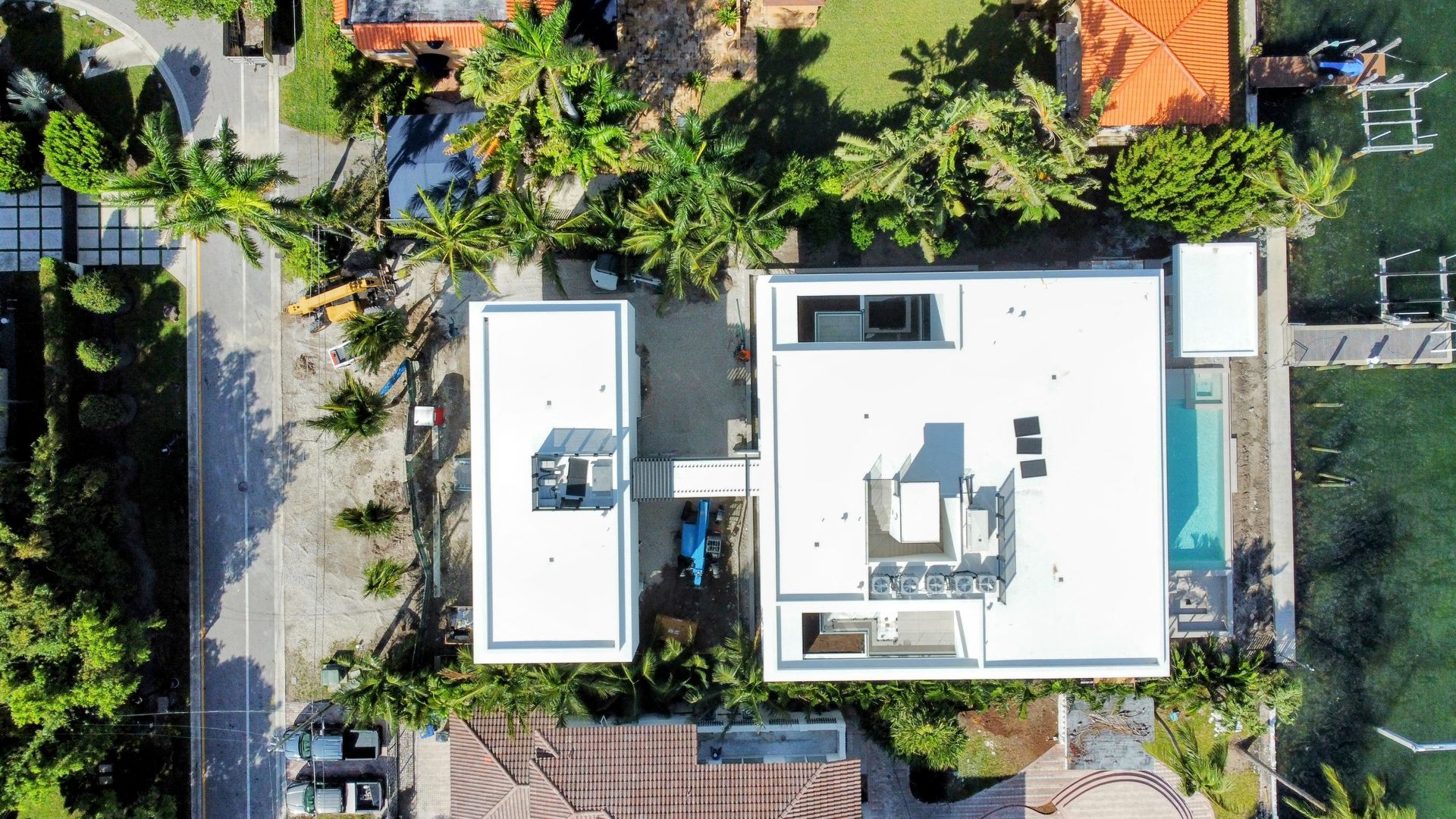 An aerial view of a house with a pool in the middle of a residential area.