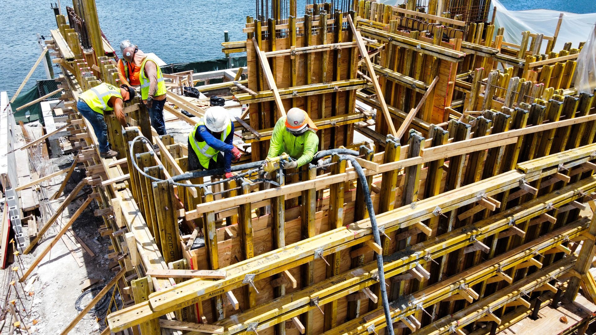 Construction workers pouring concrete into wooden forms on a construction site.