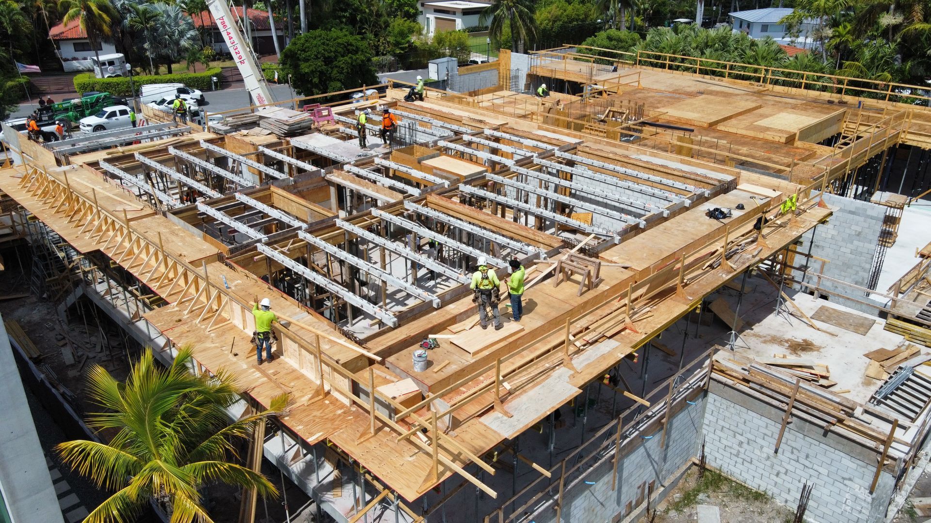 Construction site with wooden framework, workers, and a crane.