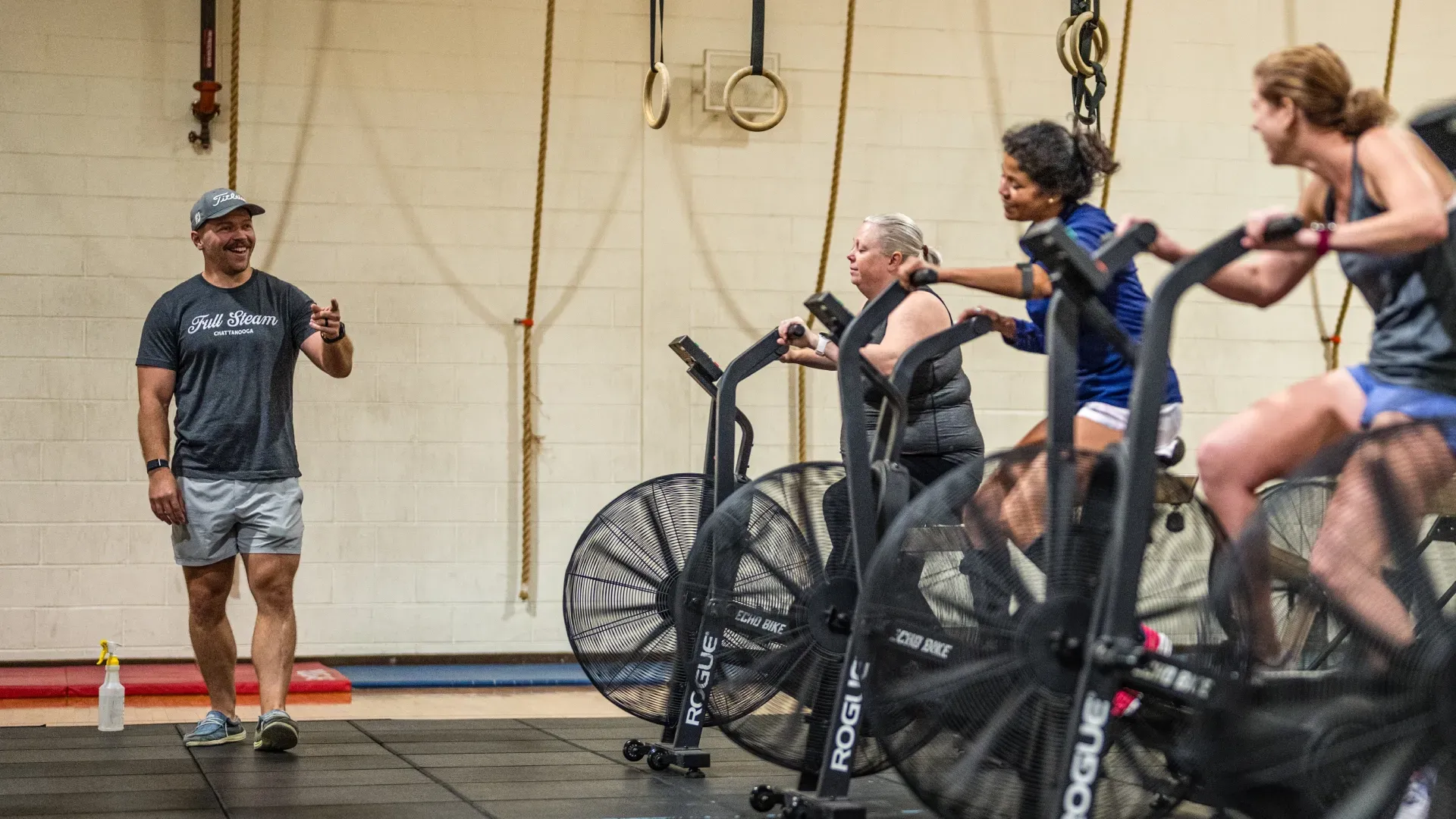 Instructor talks to cyclists on stationary bikes in an indoor studio