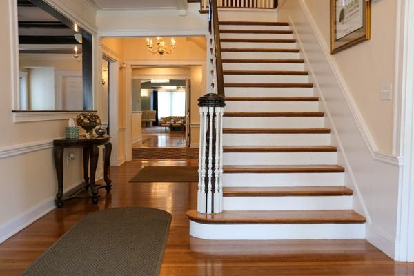 Entryway with staircase, hardwood floors, and table with decorations.