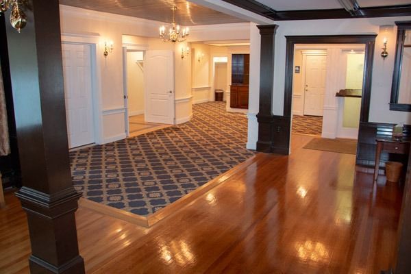 Hallway with dark wooden pillars, light walls, patterned carpet, and multiple doors.