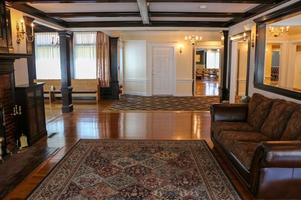 Living room with a dark wood fireplace, large rug, brown sofa, and hardwood floors.