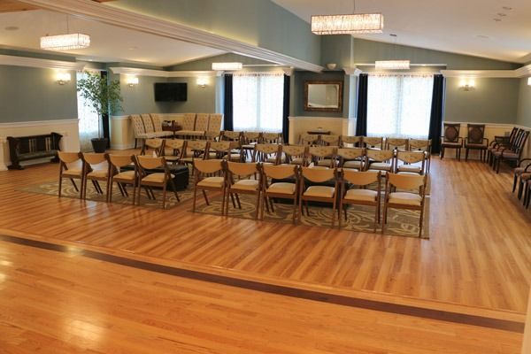An event room with rows of chairs, wooden floor, and a fireplace.