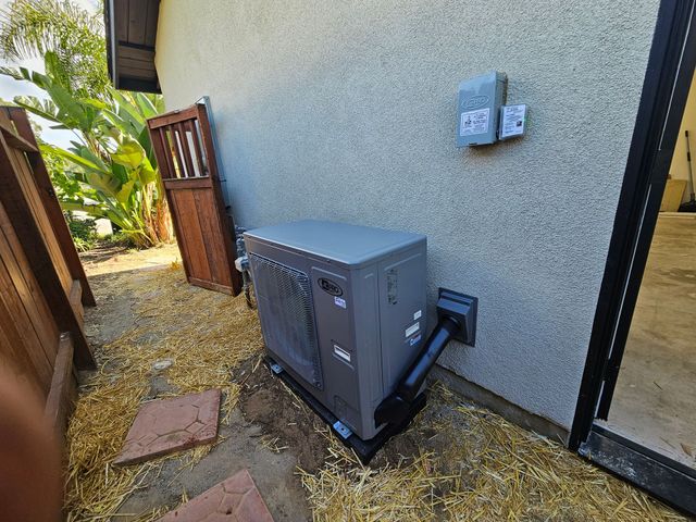 Pool heater mounted on a wall next to a sliding door.  Brown fence and door in the background.