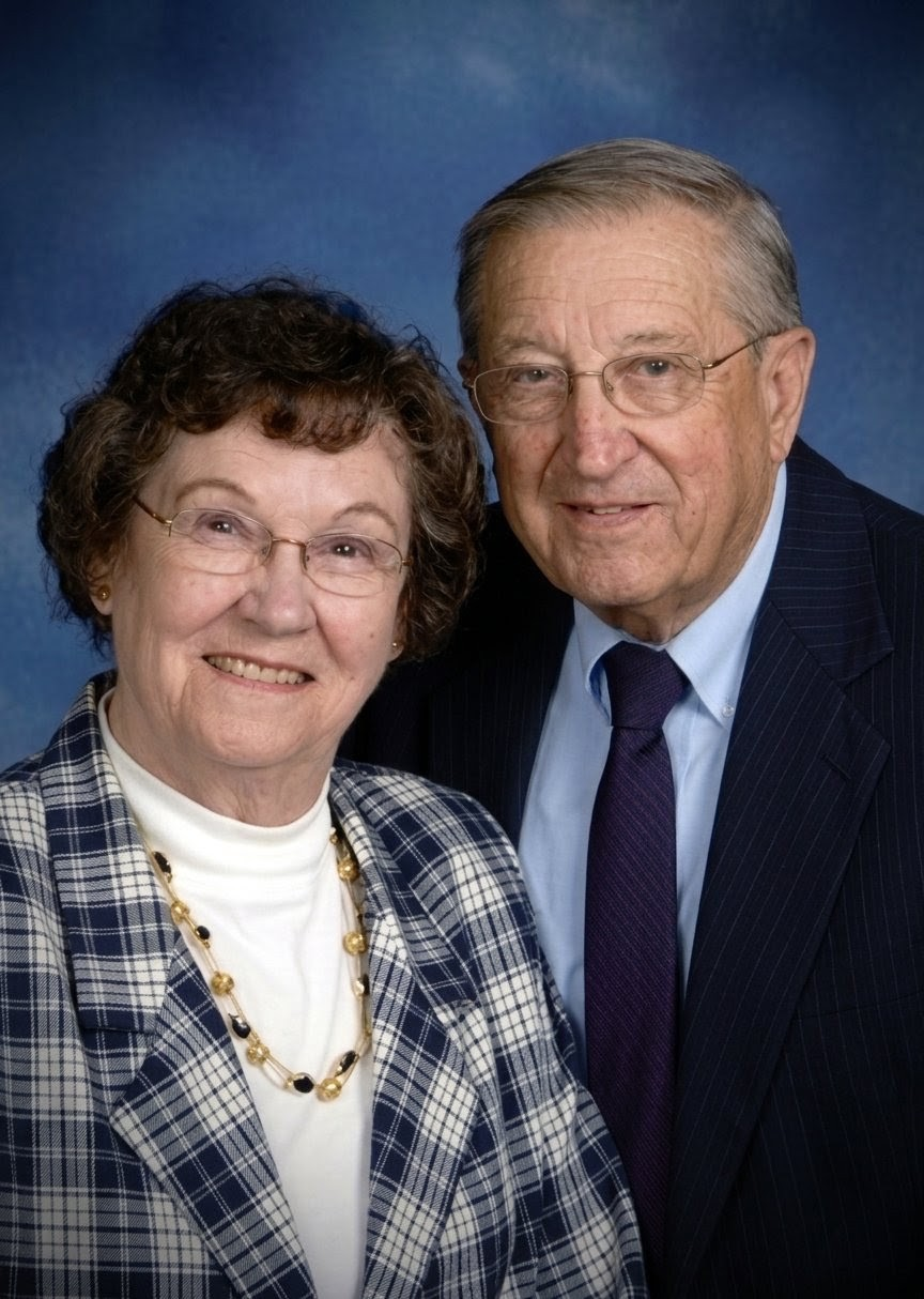 A smiling couple posing for a portrait against a blue studio background.