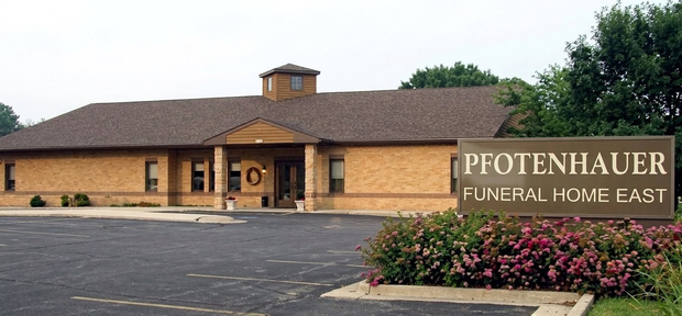 A single-story commercial building with tan metal siding, a stone base, and a central entrance under a covered porch.