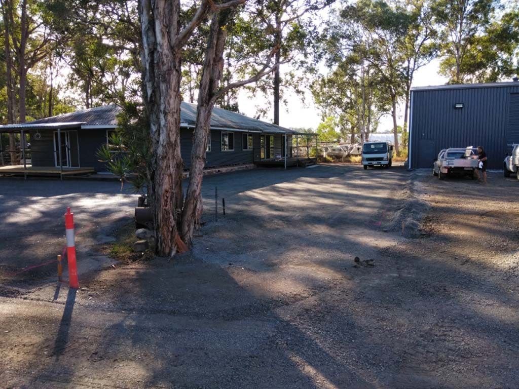 A parking lot with cars parked in front of a building surrounded by trees.