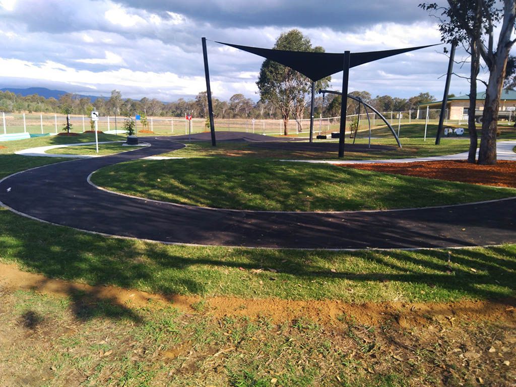 A path in a park with a black umbrella in the middle