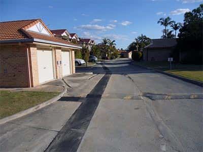 A residential street with a brick building on the right and a garage on the left.