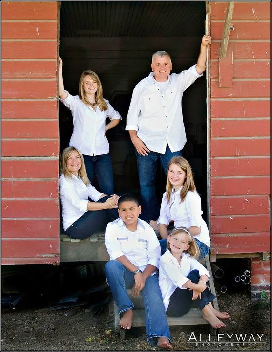Six people posing in a red doorway, with one standing and others seated on the threshold.