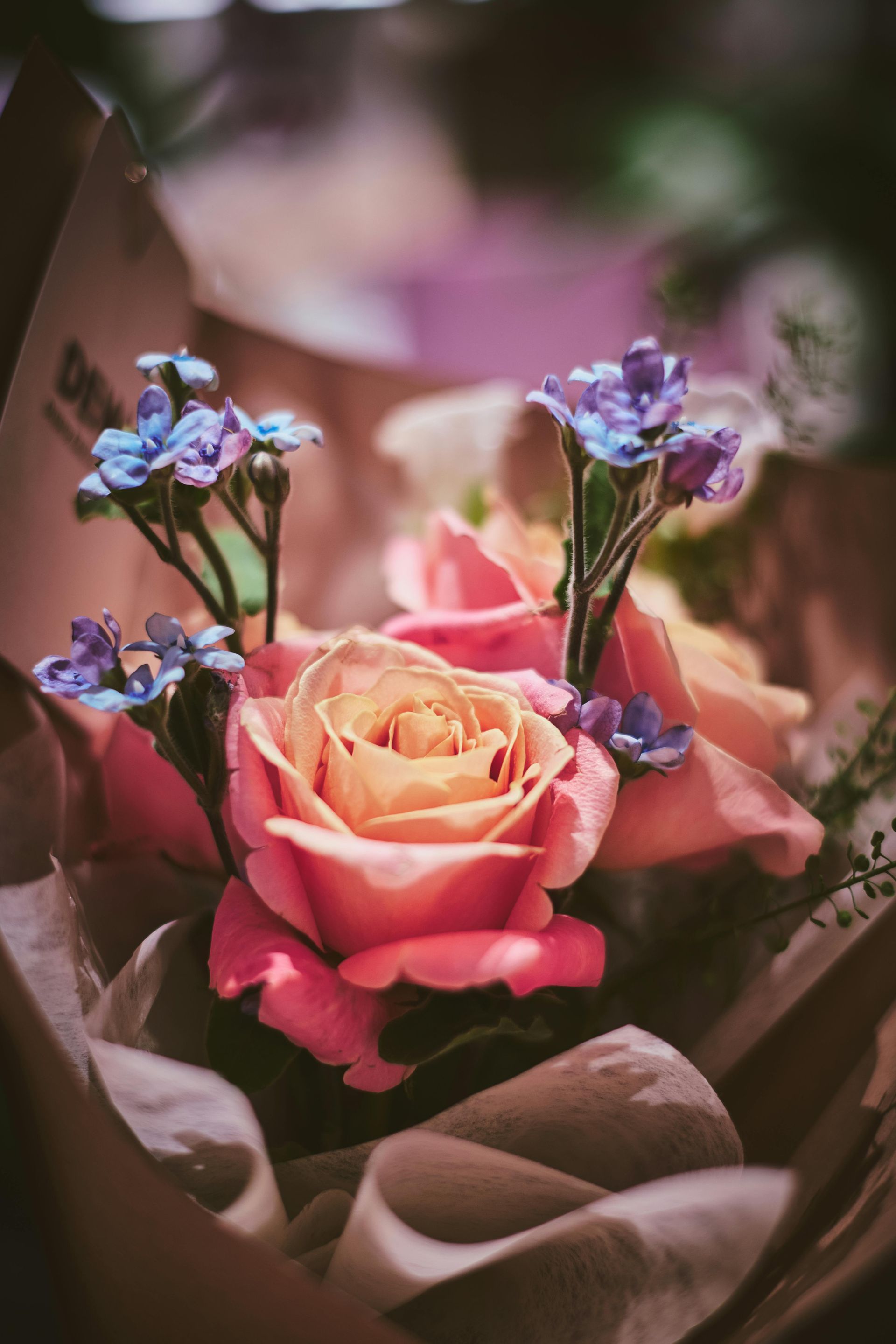 Pink rose bouquet with purple flowers wrapped in brown paper