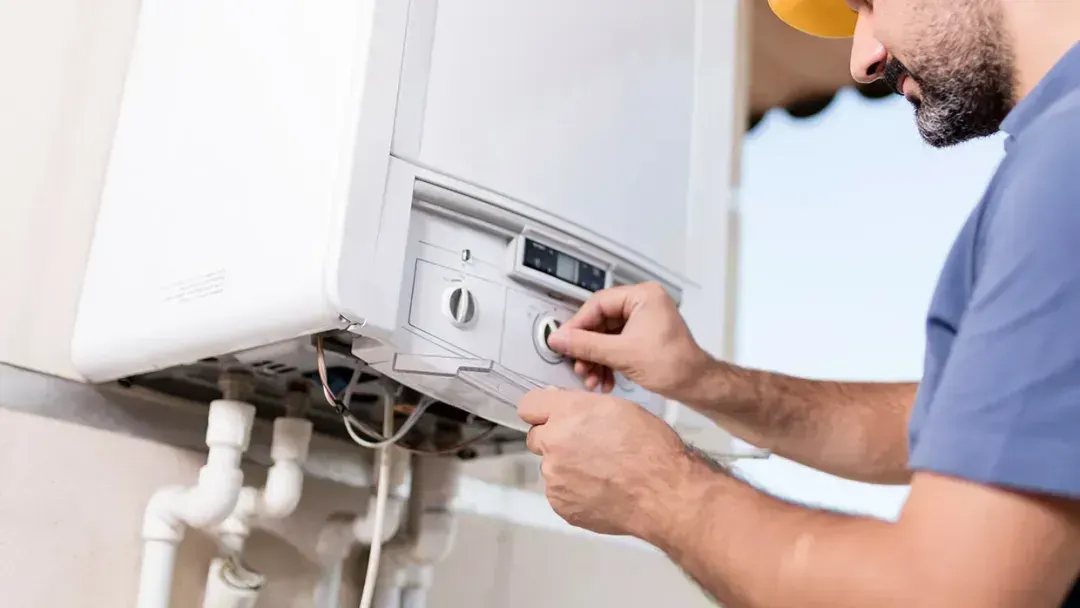 Technician adjusting a white wall-mounted boiler with a wrench