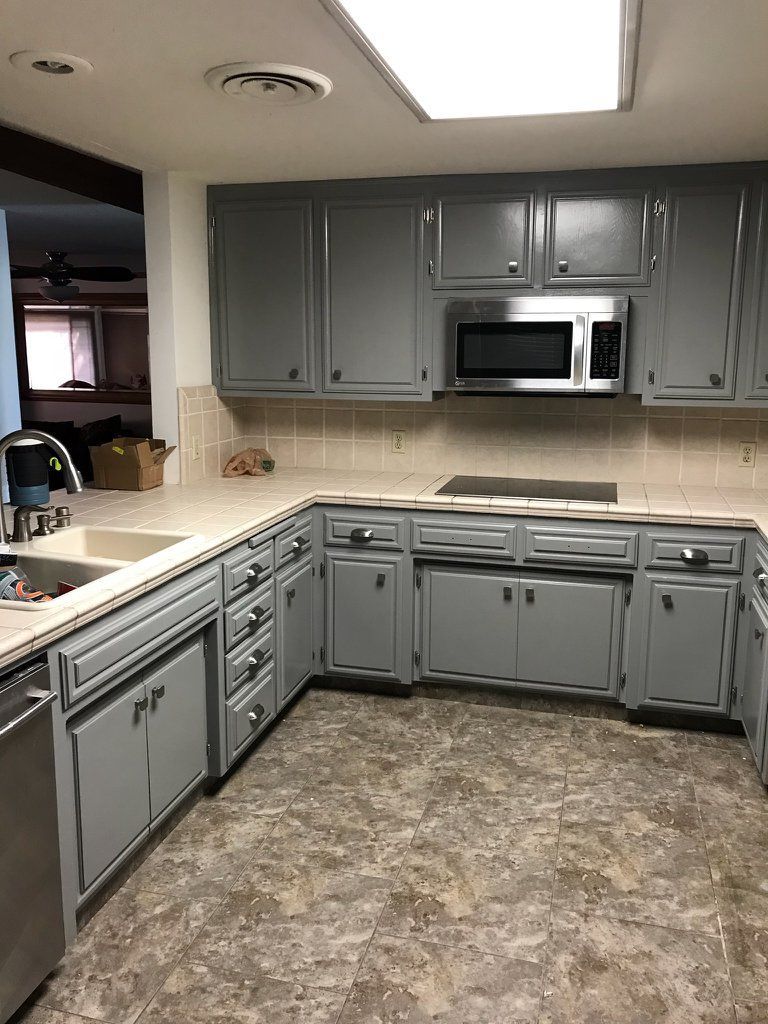A kitchen with gray cabinets , stainless steel appliances , a sink , and a microwave.