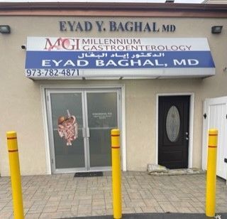 Storefront sign for Eyad Y. Baghal MD gastroenterology office with glass doors and yellow bollards