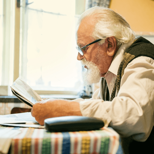 Older gentleman reading a newspaper at the table