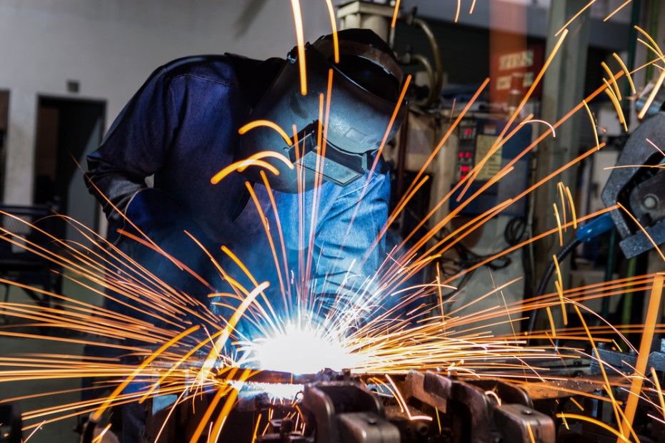 A Man is Welding a Piece of Metal in a Factory — Drinnan's Diesel & Automotive Repairs In Gladstone Central, QLD