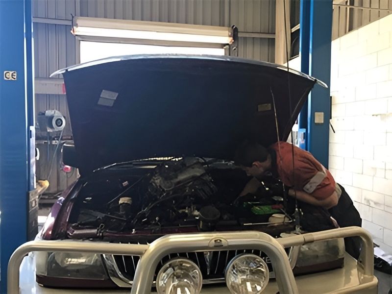 A Man is Working on a Car With the Hood Open in a Garage — Drinnan's Diesel & Automotive Repairs In Gladstone Central, QLD