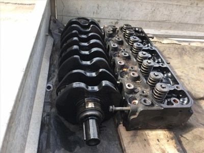 A Crankshaft and Cylinder Head Are Sitting on a Wooden Table — Drinnan's Diesel & Automotive Repairs In Gladstone Central, QLD